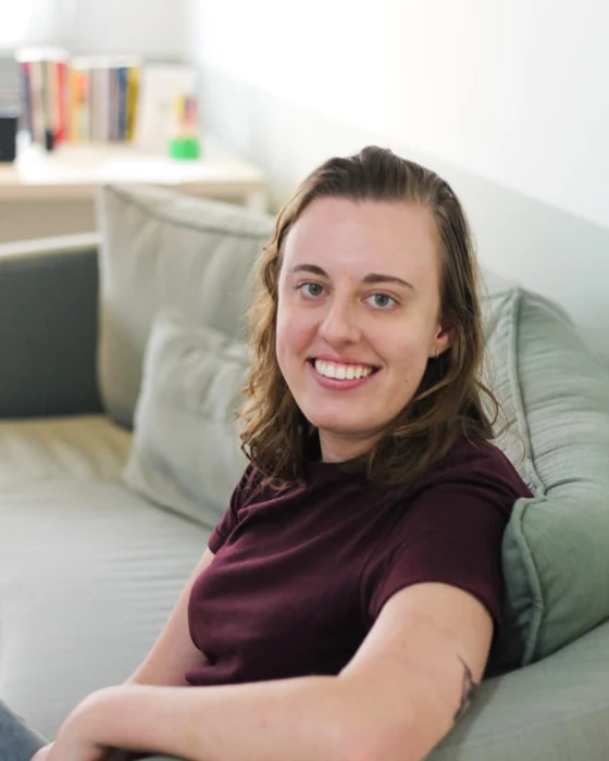 Ana Paula sorrindo, sentada num sofá verde